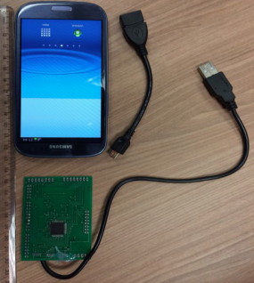 A suspicious smartphone next to a simple one-chip board and a pair of cables