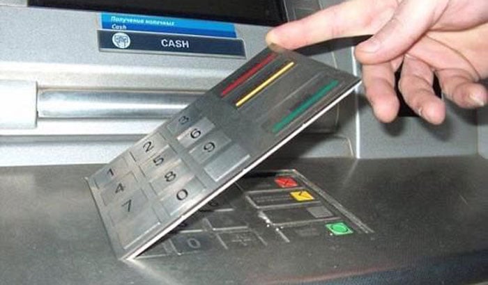 Image of the hand lifting the hidden ATM PIN skimmer
